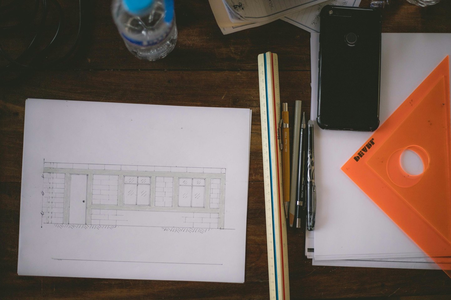 Architectural drawing and design tools on a wooden desk.
